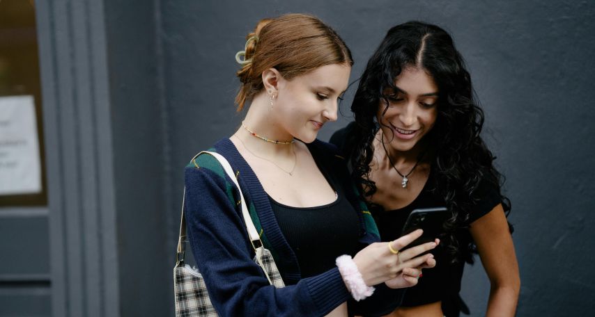Women Smiling while Looking at the Smartphone