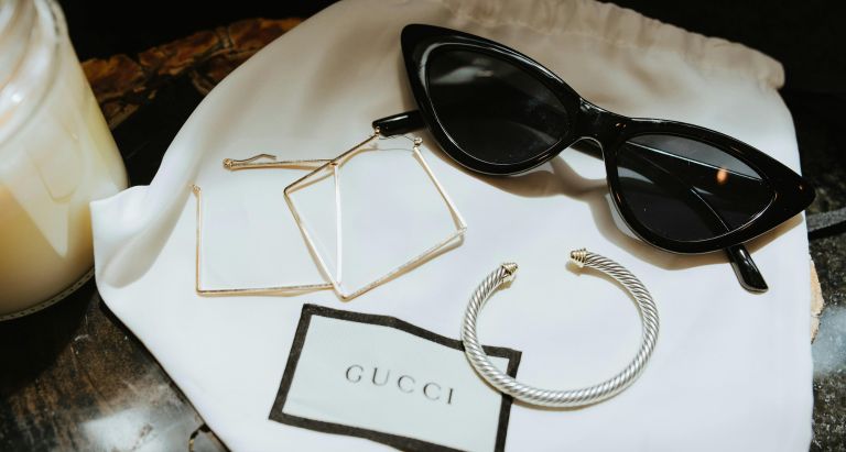 Black Framed Sunglasses and Jewellery on a Gucci Dust Bag